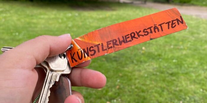 Hand mit Schlüsselbund auf dem "Künstlerwerkstätten" steht