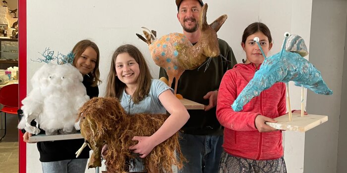 Foto: Holzdesigner Florian Schmigalle mit seinen Teilnehmerinnen und den Ergebnissen. © Stadtverwaltung Erfurt/G. Becher Drei Mädchen und ein Mann welche künstlerische Tierfiguren halten