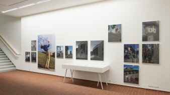 Eine Wand mit vielen verschieden großen Bildern auf dem Boden lose Zettel mit einer kleinen Treppe