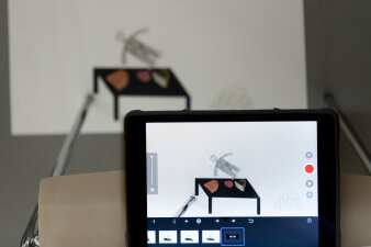 Foto: Im Workshop werden gemeinsam mit Medienkünstlerin Susanna Hanna Trickfilme gedreht. © Stadtverwaltung Erfurt / D. Urban Ein Tablet welches gerade einen Film von einer Zeichnung einer Figur und einem Tisch aufnimmt.