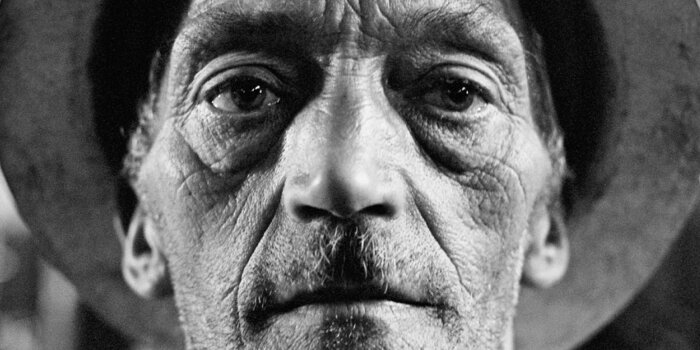 Ein schwarz weiß Portrait eines alten Mannes mit Hut, darüber in weißer Schrift „Hugo Jaeggi“