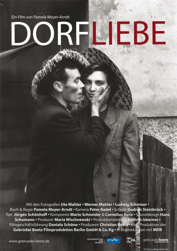 Plakat zum Dokumentarfilm „Dorfliebe“ (2010) Schwarz Weiß Bild eines Pärchens, darüber Überschrift Dorfliebe, darunter weiße Schrift