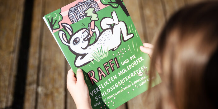 ein Kind hält ein Plakat in der Hand, auf dem ein stilisiertes weißes Kaninchen abgebildet ist