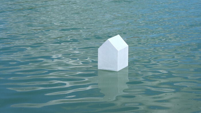 Ein Papierhaus schwimmt auf Wasser