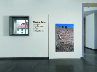 weiße Wand mit Fenster und Schriftzug, daneben eine Fotografie einer Landschaft