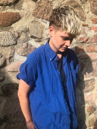Foto: Biba Nass © Biba Nass Stehende Person mit blauem Oberteil vor einer Steinwand