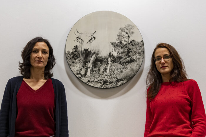 Künstlerin Valentina Murabito (l.) und Kuratorin Suzan Kizilirmak (r.) zur Pressekonferenz Zwei Frauen die in die Kamera blicken, zwischen ihnen ein rundes schwarz weißes Bild einer Kuh