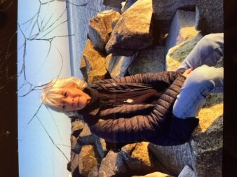 Foto: Lyrikerin Christina Klauke © Privataufnahme Frau mittleren Alters sitzt auf großen Steinbrocken am Meer