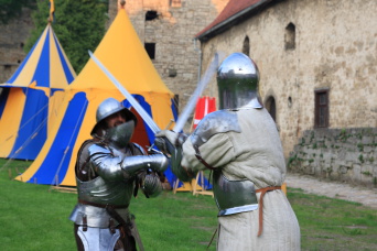 Zwei Männer in mittelalterlichen Ritterrüstungen beim Schwertkampf.