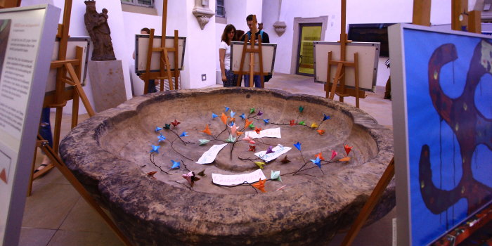 Foto: "Wasser-Kunst" im Trocknen: Die Brunnenschale des alten Petersklosters im Foyer des Angermuseums bot ein wunderbares Ambiente für die moderne Kunst © Stadtverwaltung Erfurt / I. Hettstedt Gefaltete Blüten in Steinschale, um diese herum präsentierte moderne Kunst.