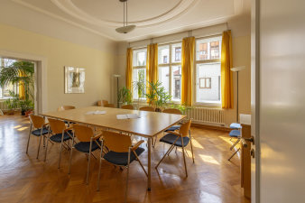 großer Tisch mit Stuhlen in der Mitte eines Raumes vor einer Fensterfront