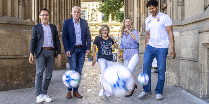 fünf Personen kicken Fußbälle