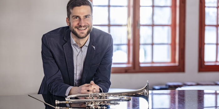 Leiter der Musikschule Marcus Kuhn lehnt auf einem Konzertflügel, eine Trompete liegt vor Ihm auf dem Flügel.