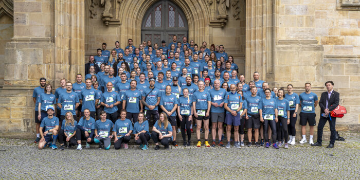 sehr viele Menschen in Sportkleidung mit einheitlichen, grau-blauen T-Shirts