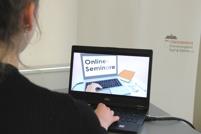 Online-Seminar Farbfoto. Eine Frau sitzt vor einem Laptop