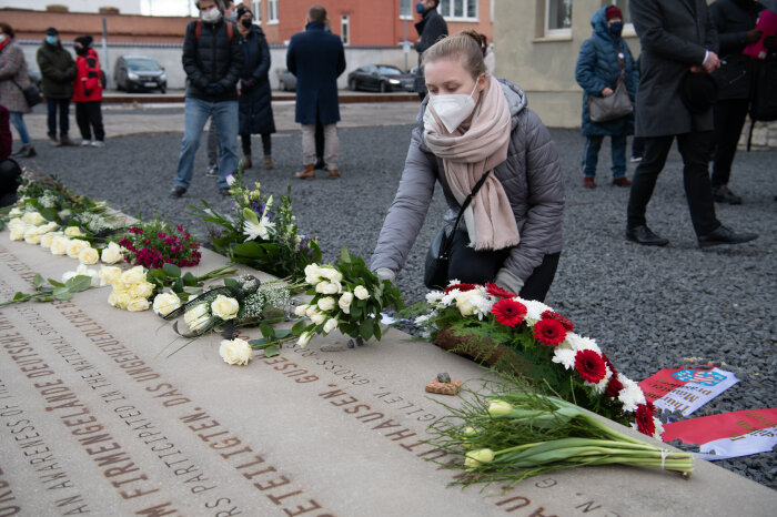 Eine Besucherin legt Blumen am Stein der Erinnerung vor dem ehemaligen Verwaltungsgebäude von J. A. Topf & Söhne nieder, 27. Januar 2022 Eine Frau legt Blumen auf eine Steinplatte