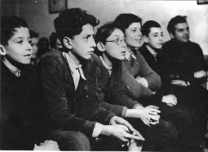 Kinder Gaudiopolis Schwarz Weiß Foto von Kindern die in einer Reihe sitzen