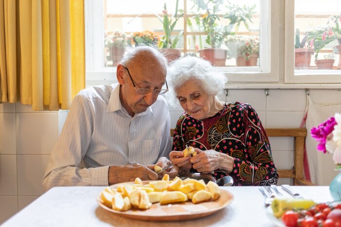 ein ältere Mann und eine ältere Frau zerkleinern Äpfelstücke