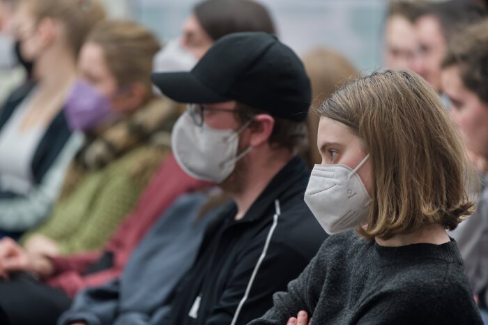 jugendliche mit Maske die in einer Reihe sitzen