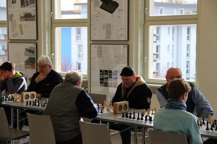 Eindrücke vom letzten Königsgambit-Gedenkturnier am Erinnerungsort Topf & Söhne, 25. November 2023 Mehrere Personen an einem langen Tisch die Schach spielen