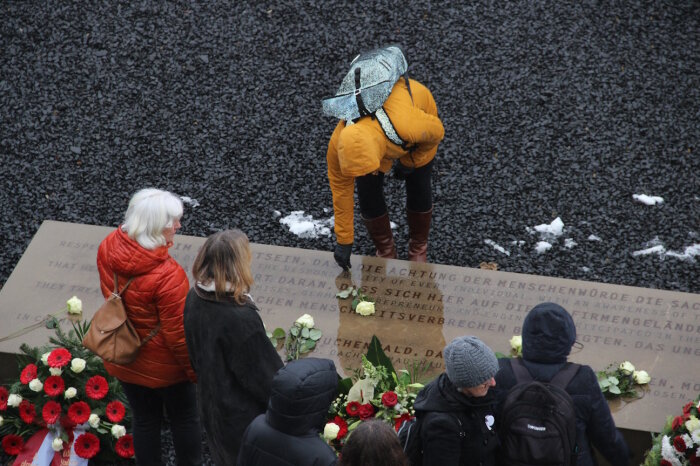 Gedenken am Stein der Erinnerung Mehrere Personen an einem Gedenkstein die Blumen niederlegen