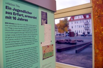 Eine Ausstellungstafel mit einem Schwarz-Weiß-Foto und einer Kinderzeichnung, im Hintergund ist ein Fenster.