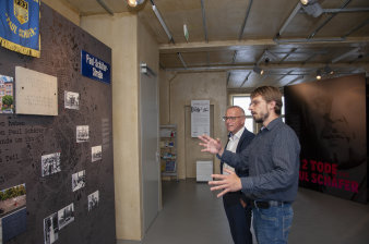 Zwei Männer betrachten Ausstellungstafeln. 