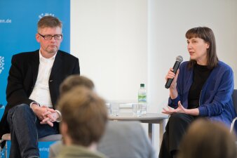 ein Mann und eine Frau mit Mikrofon die am Tisch sitzen