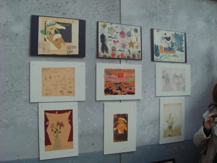 Kinderzeichnungen in der Ausstellung "Die Mädchen von Zimmer 28. L 410, Theresienstadt" An einer Wand hängen neun Kinderzeichnungen und Gemälde.