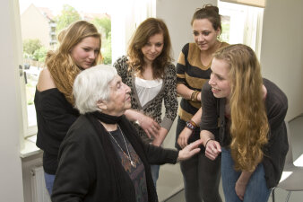 Vier junge Frauen im Gespräch mit einer alten Dame