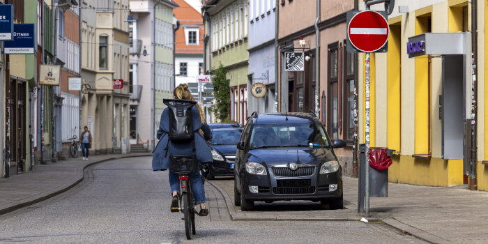eine Frau fährt verkehrtherum mit dem Fahrrad in eine Einbahnstraße
