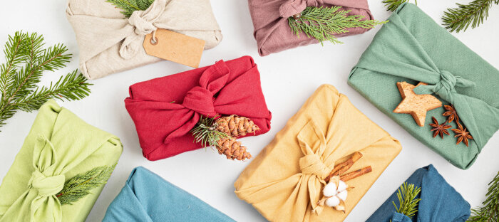 Nachhaltige Geschenkverpackung mit Furoshiki Bunte Geschenke nachhaltig in Tücher verpackt mit Tannenzapfen und -zweigen
