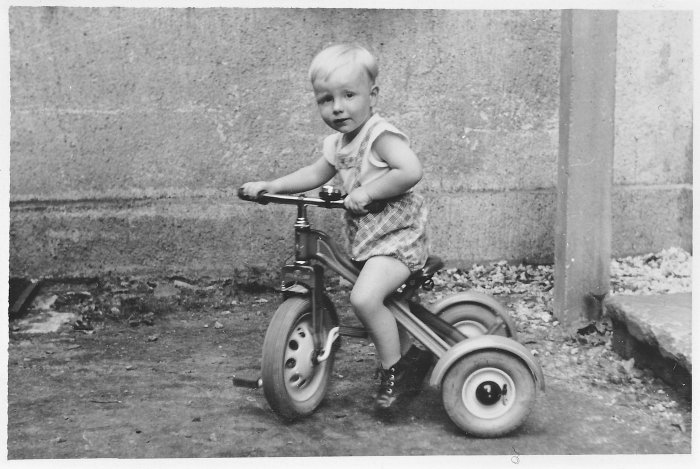 Schwarz-weiß-Foto eines kleinen Kindes auf einem Dreirad