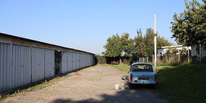 ein Trabant steht an einer Garagenanlage