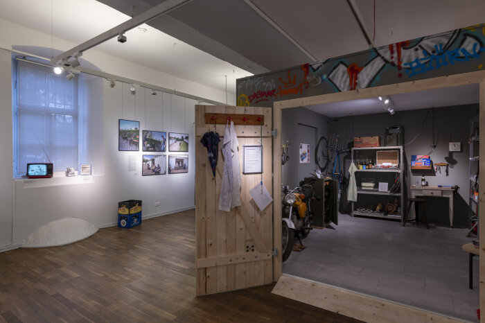 Einblick in die Sonderausstellung Offenes Garagentor aus Holz, im inneren Regale mit allerlei drin