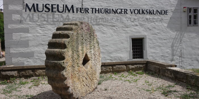 großes Steinrad vor Hauswand mit der Schrift Museum für Thüringer Volkskunde